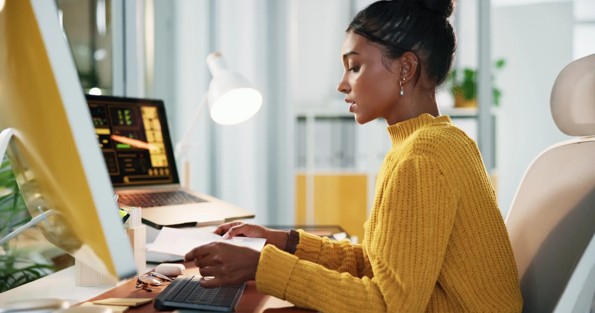 A woman reviewing financial documents at a laptop